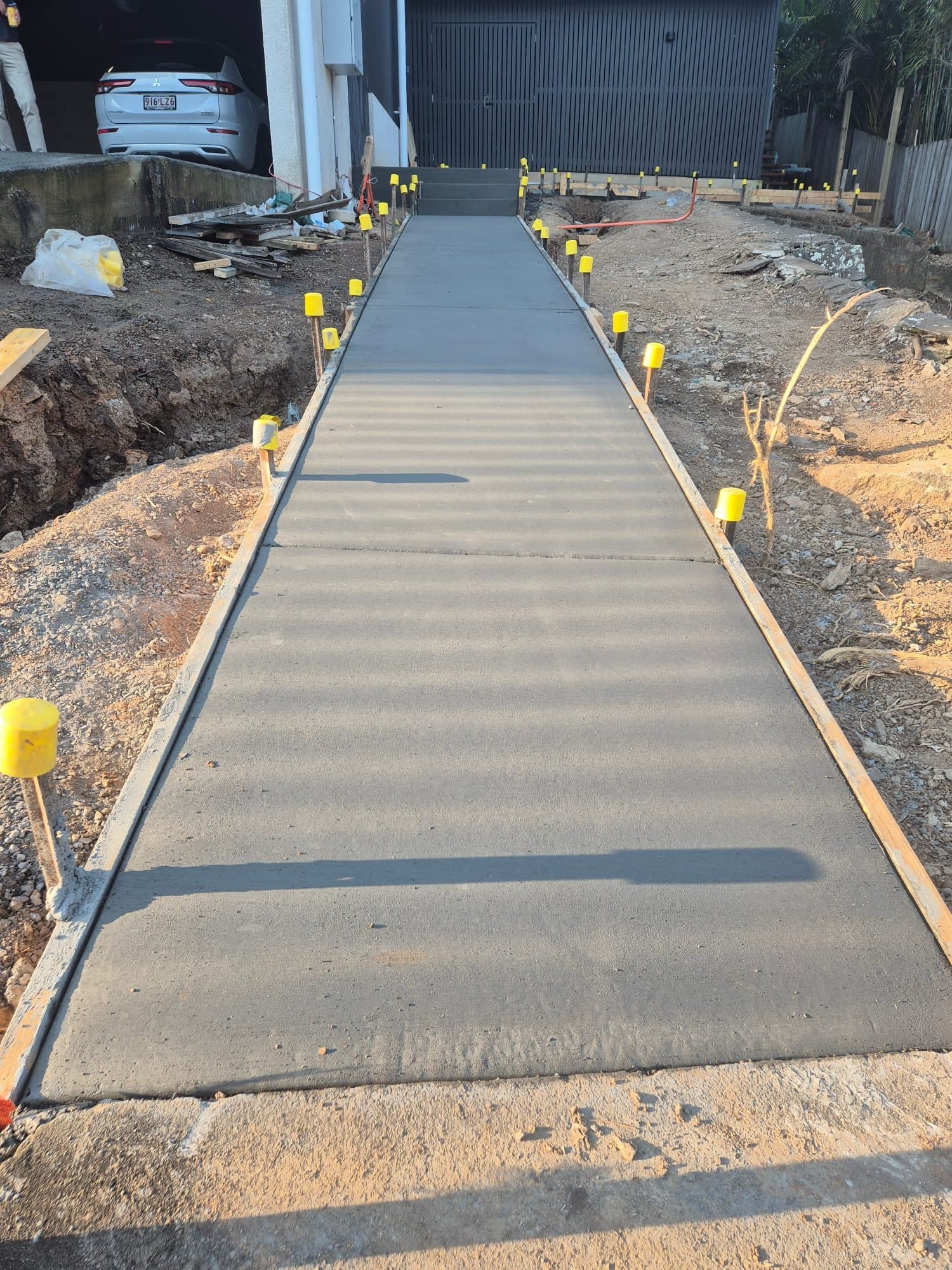 Freshly poured concrete path with a broom finish beside a home