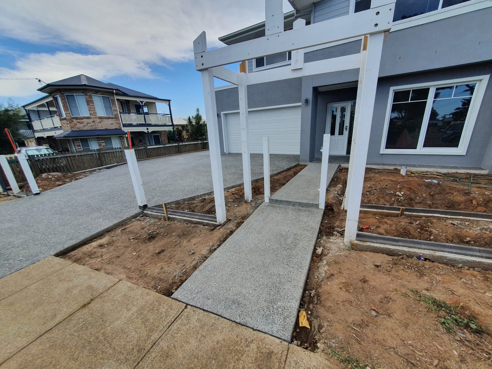 New concrete driveway and entrance path leading to a home's front door